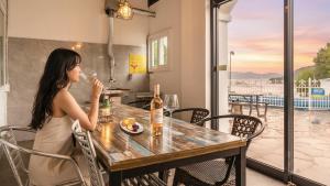a woman sitting at a table with a glass of wine at Ganghwa Giverny Spa Pension in Incheon