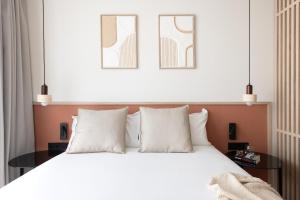 a bedroom with a white bed and two pictures on the wall at Líbere Seville Plaza Nueva in Seville
