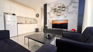 a living room with a table and a tv on a wall at דירת 2 חדרים בטיילת בת ים in Bat Yam