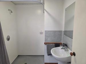 ein weißes Badezimmer mit Waschbecken und Dusche in der Unterkunft Palmcourt Motel in Westport + 20 Fotos