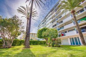 a large building with palm trees in front of it at NEW Apt Relax Home a 150 m del mar, WIFI y Piscina in Port d'Alcudia