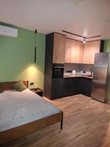 ein Zimmer mit einem Bett und einer Küche mit Kühlschrank in der Unterkunft Green house в центрі міста in Irpin + 4 Fotos