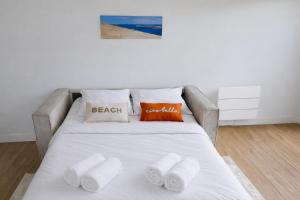 un letto con lenzuola bianche e cuscini arancioni sopra di Vaste studio 3 personnes avec balcon et parking a La Teste-de-Buch