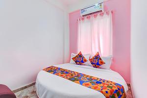 a bedroom with a bed with colorful sheets and a window at Via Pink House in Pune