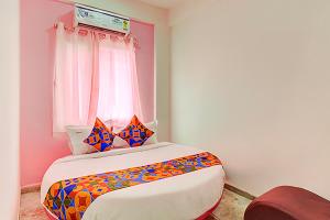 a bedroom with a bed with colorful pillows and a window at Via Pink House in Pune