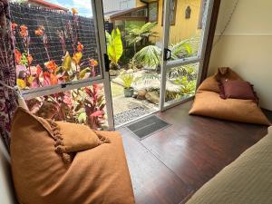 a porch with two pillows and a large window at Pandora Cottage Beachfront in Raglan