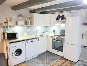 una cucina con mobili bianchi, lavatrice e asciugatrice di Le Gite Leiloo a La Puye Altre 5 foto