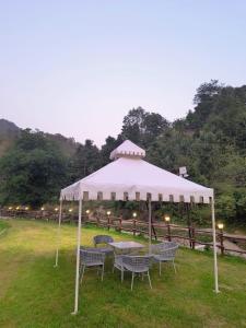 ein weißes Zelt mit Stühlen und einem Tisch auf einem Feld in der Unterkunft Nature Camp in Nainital