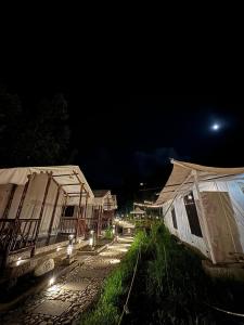 eine Reihe von Zelten bei Nacht mit dem Mond in der Unterkunft Nature Camp in Nainital