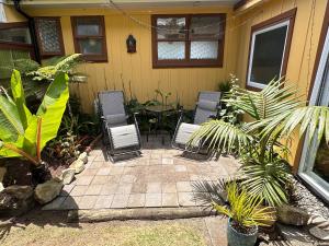 a patio with chairs and a table in front of a house at Pandora Cottage Beachfront in Raglan
