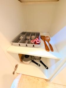 ein weißes Regal mit Utensilien in einer Küche in der Unterkunft Vortex Suites KLCC By Comforthome in Kuala Lumpur + 1 Foto