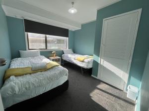 um quarto com paredes azuis, uma cama e uma janela em The Sweet Pea- Room 4 em Hamilton