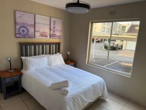 ein Schlafzimmer mit einem großen weißen Bett mit einem Fenster in der Unterkunft 37 Laguna La Crete in Margate + 10 Fotos