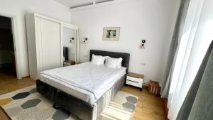 a bedroom with a bed with white sheets and pillows at Parc Vatra Dornei - Deluxe Suite in Vatra Dornei