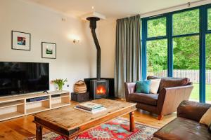 een woonkamer met open haard en tv bij Glenardle Lodge in Bridge of Cally