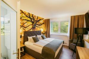 a bedroom with a bed with a tree mural on the wall at Waldhotel Ehrental in Schmalkalden