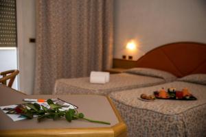 um quarto de hotel com duas camas e uma mesa com flores em New Petit Hotel em Tempio Pausania