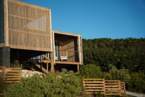 a wooden house with a balcony and a fence at Seaview Container Studio in Gansbaai