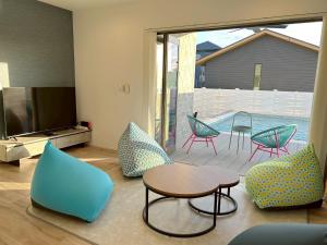 Una sala de estar con sillas, una mesa y un televisor. en THE POOL HOUSE Kisarazu, en Kuguta