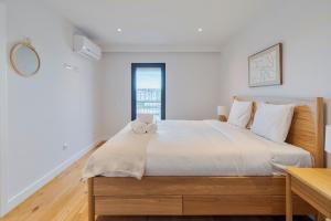 una camera da letto con un letto grande con lenzuola bianche di Lume Residence W a Setúbal