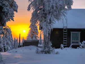 a house in the snow with the sunset in the background at Hietavilla Aurora - Hot tube - Sauna - AC - Fireplace - 11kW EV-refuel - Landscape view - Silence - Free WiFi in Ruka