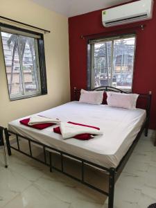 uma cama com paredes vermelhas e toalhas brancas em Hil min apartment Calangute em Calangute