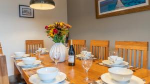 een tafel met een fles wijn en een vaas met bloemen bij Woodside Cottage in Chipping Campden +17 foto's