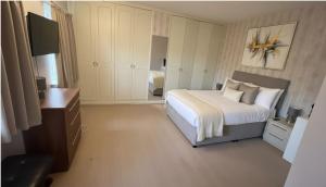 een slaapkamer met een bed, een bureau en een televisie bij The London Residence in Enfield