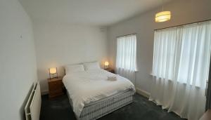 een witte slaapkamer met een bed en een raam bij The London Residence in Enfield