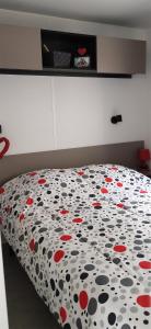 Schlafzimmer mit einem Bett mit roten und schwarzen Blumen in der Unterkunft Mobil home famille Calazel in Sérignan