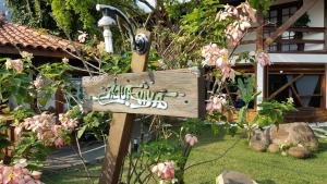 a wooden sign in a garden with pink flowers at Pousada Agua Viva in Abraão