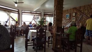a group of people sitting at tables in a restaurant at Pousada Agua Viva in Abraão