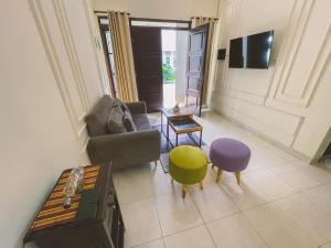 a living room with a couch and chairs and a tv at Avana Guesthouse in Kalasan