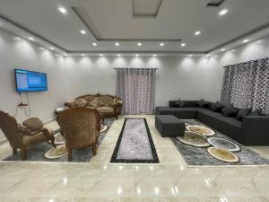 un salon avec un canapé, des chaises et une télévision dans l'établissement La Dolce Villa with Private Pool, à Borg El Arab