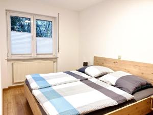 a bed in a bedroom with two windows at Ferienwohnungen Weingut Breit in Piesport
