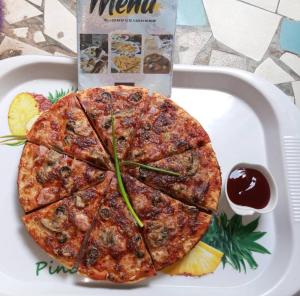 una pizza su un piatto bianco su un tavolo di Monique CZ Abomey Plage ad Abomey