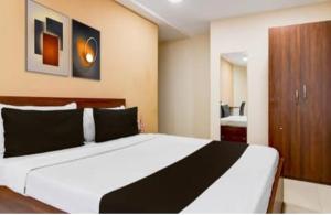 ein Schlafzimmer mit einem großen weißen Bett mit schwarzen Kissen in der Unterkunft Gokul Residency in kolkata