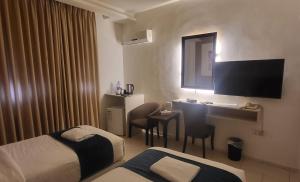 a hotel room with two beds and a desk and a television at Jordan View Hotel in Amman