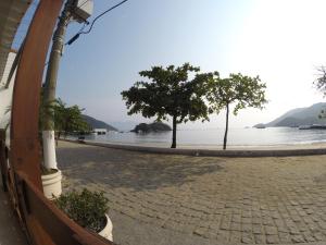 two trees on a sidewalk next to the water at Pousada Agua Viva in Abraão