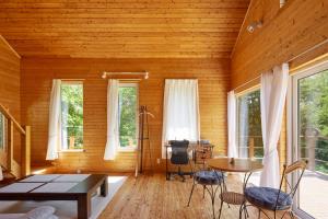a room with a table and chairs and windows at Tokachi Mikage forest villa in Mikage