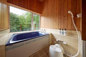 a bathroom with a tub and a toilet and a window at Tokachi Mikage forest villa in Mikage