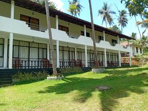 een gebouw met palmbomen ervoor bij Goyambokka Beach front pool resort in Tangalle