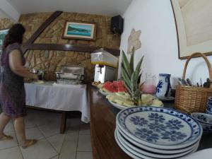 a woman standing in a kitchen with plates on a counter at Pousada Agua Viva in Abraão