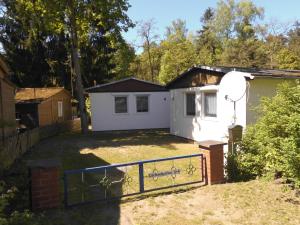 a white house with a gate in the yard at Ferienbungalow Fleesensee in Malchow