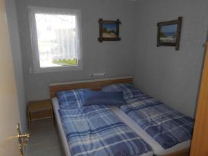 a bedroom with a bed with blue sheets and a window at Ferienbungalow Fleesensee in Malchow