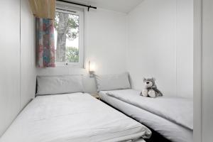 une chambre avec deux lits avec un ours en peluche assis dessus dans l'établissement KNAUS Campingpark Eckwarderhörne, à Eckwarderhörne