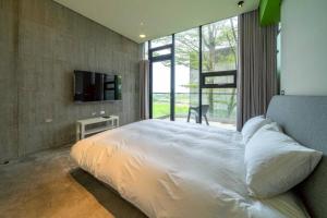 ein Schlafzimmer mit einem weißen Bett und einem großen Fenster in der Unterkunft 懶懶小日子 in Hou-hou