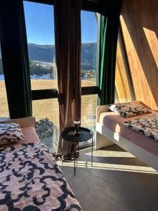 a bedroom with two beds and a large window at A Frame house Slavuljica in Vlasic