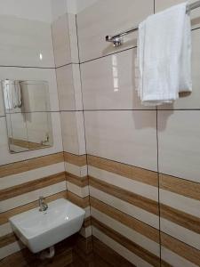 ein Badezimmer mit einem weißen Waschbecken und einem Spiegel in der Unterkunft Hilton Hill in Varkala