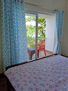Schlafzimmer mit einem Bett und einem Fenster mit einem Stuhl in der Unterkunft Hilton Hill in Varkala